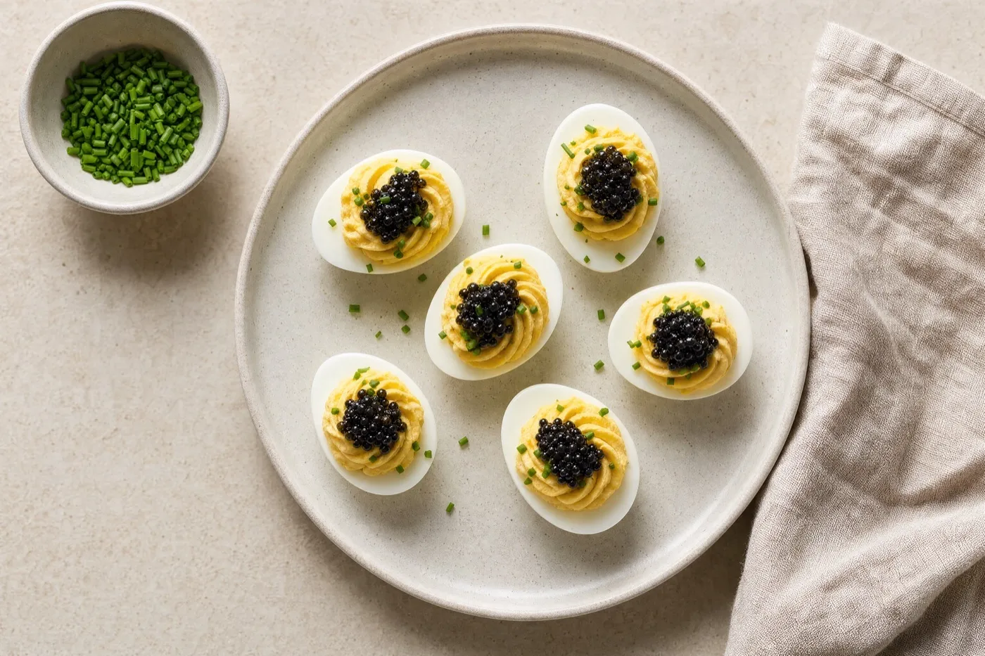 Deviled eggs each topped with a small spoon of caviar and chives.